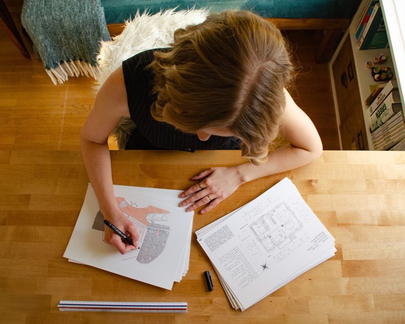 Flavie Hector dessine une perspective à côté des plans d'un projet de rénovation